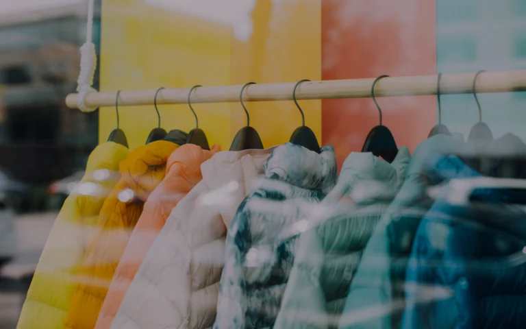 Rows of clothing hanging on racks in a retail store or warehouse.