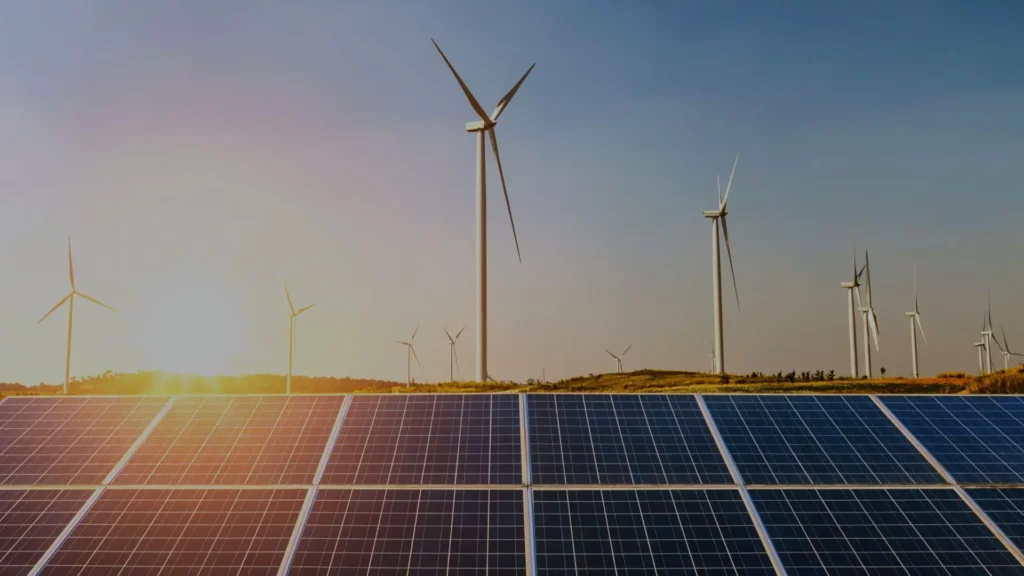 Sunset landscape featuring wind turbines and solar panels, representing renewable energy assets managed by Steadysun.